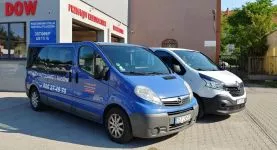 Dwa busy do wynajęcia zaparkowane przed budynkiem stacji kontroli pojazdów